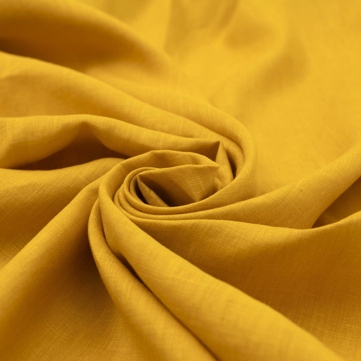 Bright summer marigold linen fabric with soft drape, breathable texture, and lightweight feel for sewing dresses, skirts, and summer apparel.