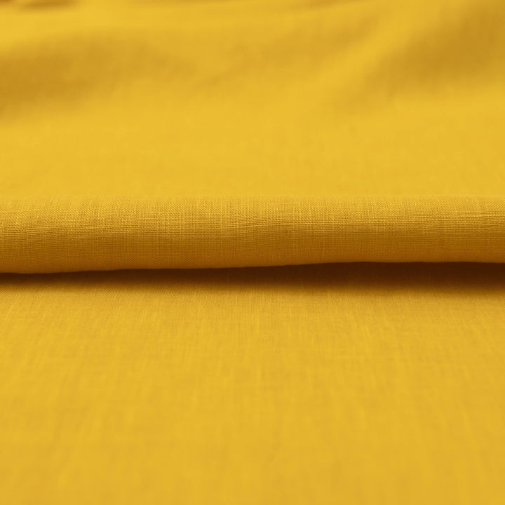 Bright summer marigold linen fabric with soft drape, breathable texture, and lightweight feel for sewing dresses, skirts, and summer apparel.