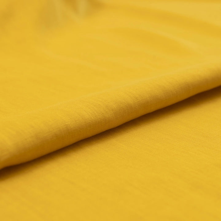 Bright summer marigold linen fabric with soft drape, breathable texture, and lightweight feel for sewing dresses, skirts, and summer apparel.