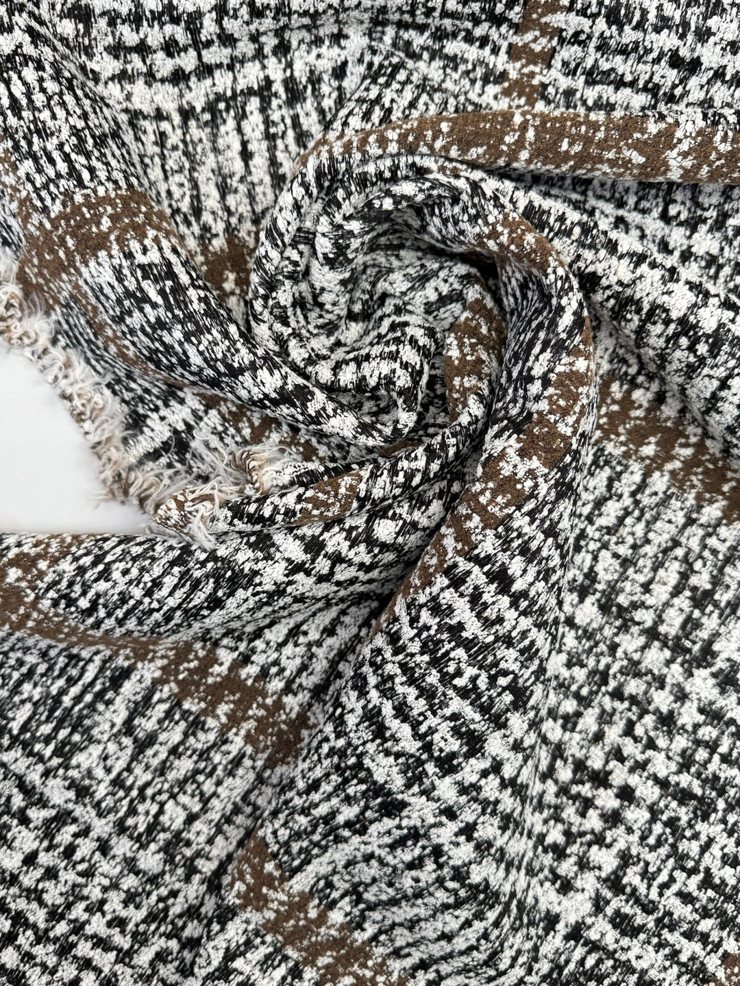 Close-up of Italian tweed fabric in wool and cotton blend, featuring white, black, and brown tones, ideal for coats, suits, and structured skirts.
