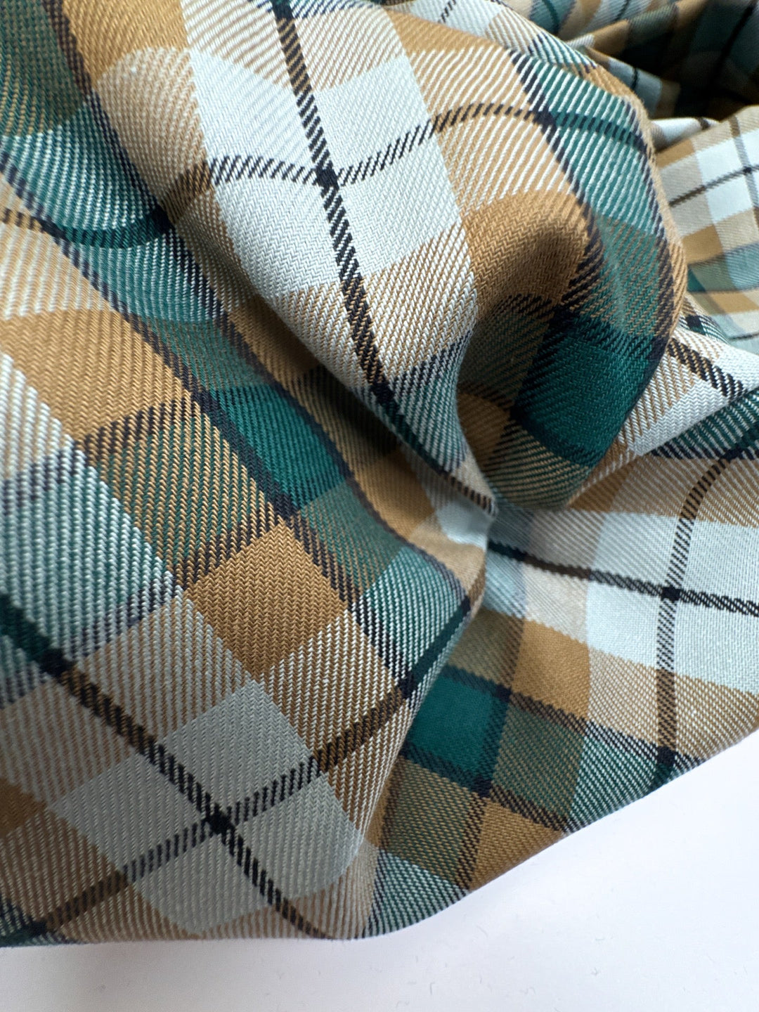 Italian cotton tweed fabric in cream, green, and brown plaid twill weave, lightweight and structured for coats, suiting, and dresses.