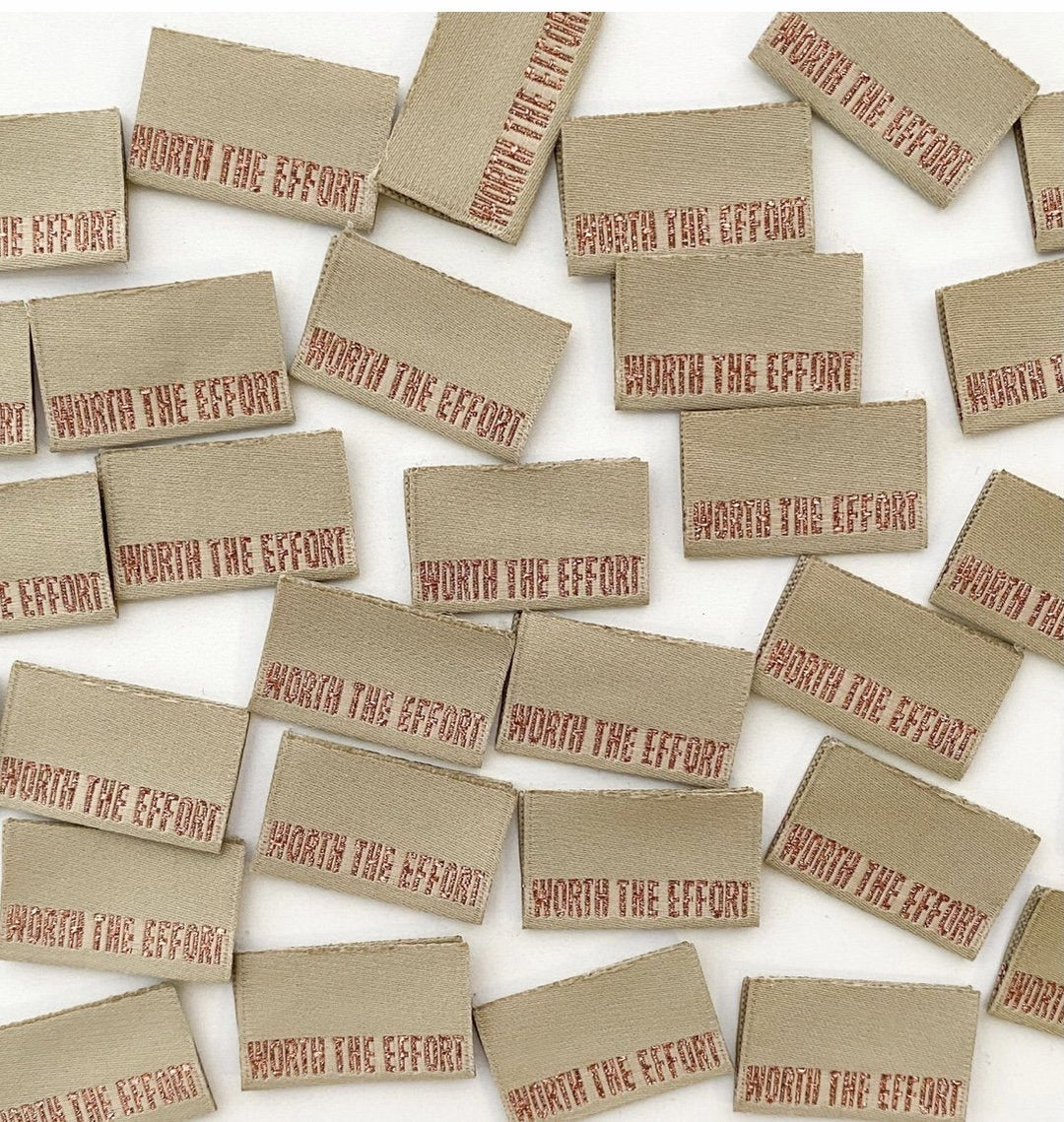 Luxury 'Worth the Effort' woven sewing labels in khaki green with rose gold metallic lettering - premium garment tags