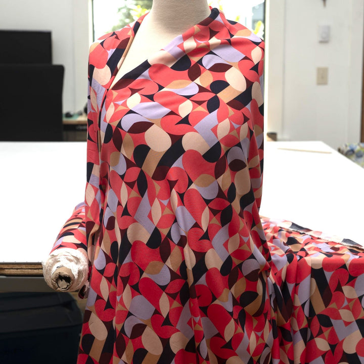 Viscose Challis "Kaleidoscope Bright" fabric featuring vibrant geometric shapes in pink, purple, black, and taupe, 58-inch width, perfect for dresses and summer garments