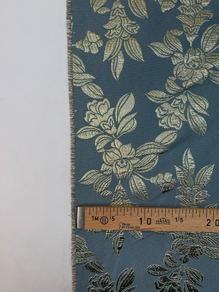 French jacquard fabric with metallic leaf pattern in teal and gold, polyester lurex acrylic blend, ideal for bridal gowns, evening dresses, and formalwear.