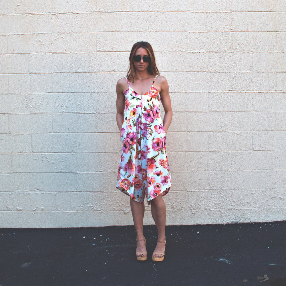 Woman wearing a stylish blue linen Fenix romper with an asymmetrical hem, showcasing the Cali Faye Collection sewing pattern.

