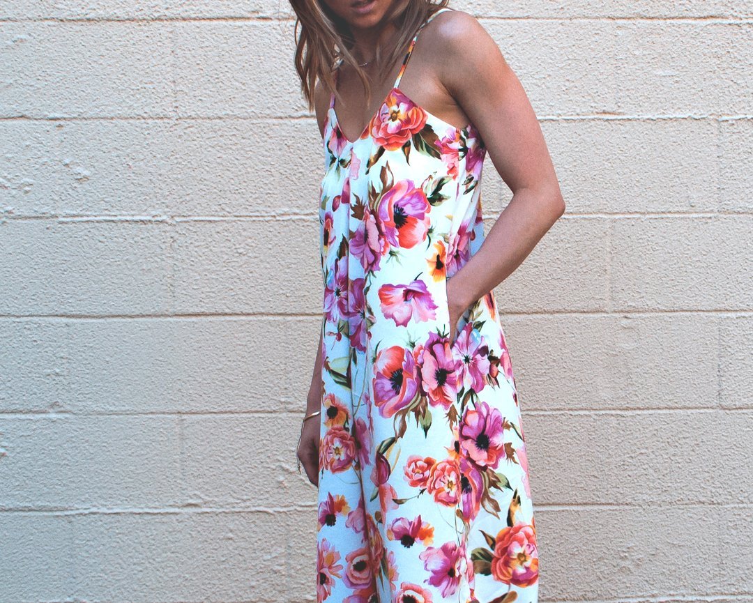 Woman wearing a stylish blue linen Fenix romper with an asymmetrical hem, showcasing the Cali Faye Collection sewing pattern.

