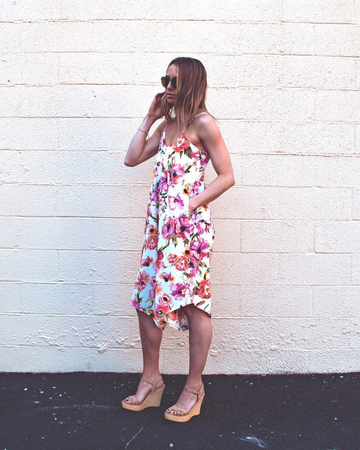 Woman wearing a stylish blue linen Fenix romper with an asymmetrical hem, showcasing the Cali Faye Collection sewing pattern.

