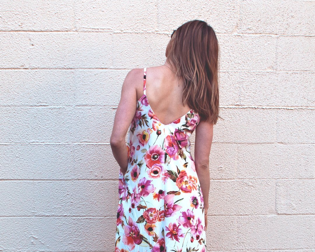 Woman wearing a stylish blue linen Fenix romper with an asymmetrical hem, showcasing the Cali Faye Collection sewing pattern.

