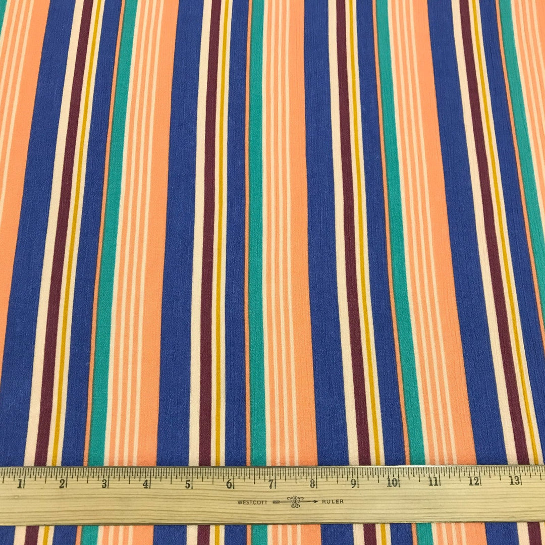Rayon Crepe Cabana Stripe fabric in peach, periwinkle, and mint colors with flowing drape