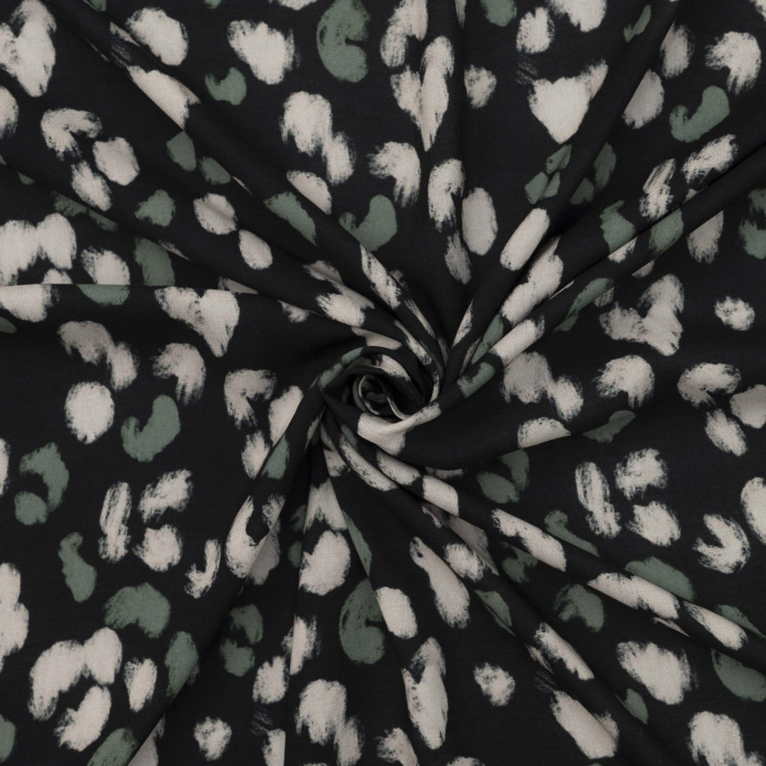 Rayon Challis fabric in black with scattered olive dots, perfect for sewing blouses, dresses, and skirts.