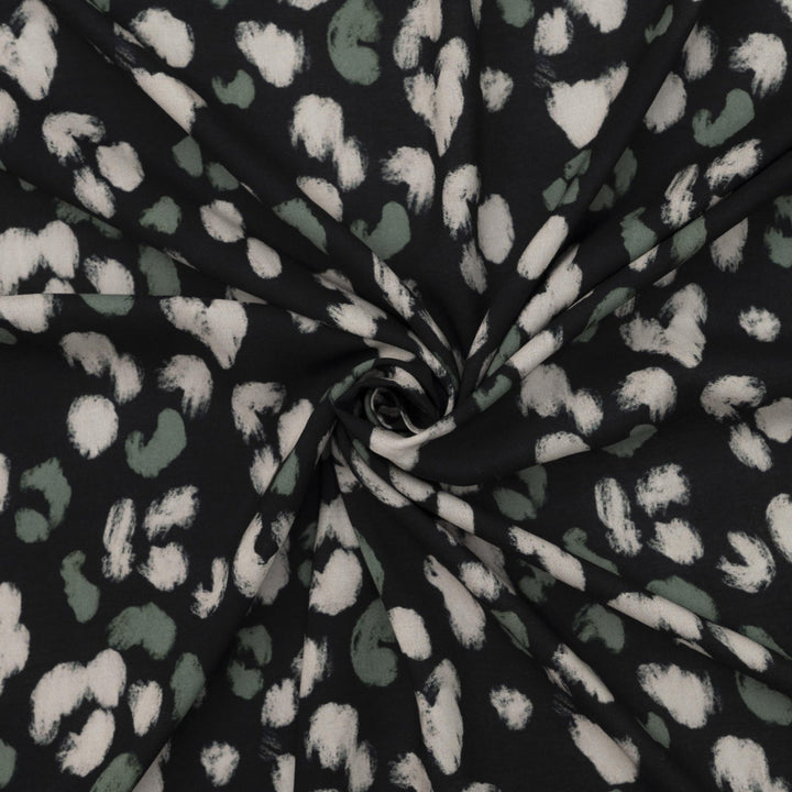 Rayon Challis fabric in black with scattered olive dots, perfect for sewing blouses, dresses, and skirts.