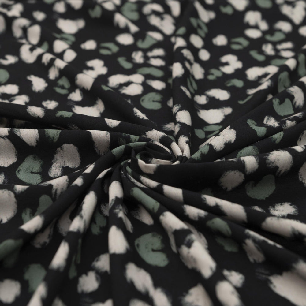 Rayon Challis fabric in black with scattered olive dots, perfect for sewing blouses, dresses, and skirts.