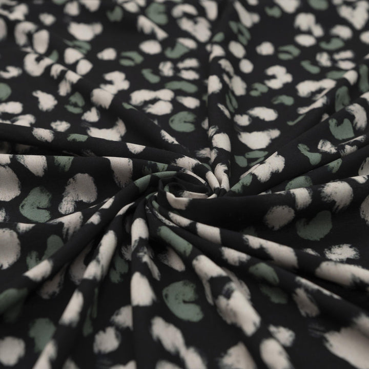 Rayon Challis fabric in black with scattered olive dots, perfect for sewing blouses, dresses, and skirts.