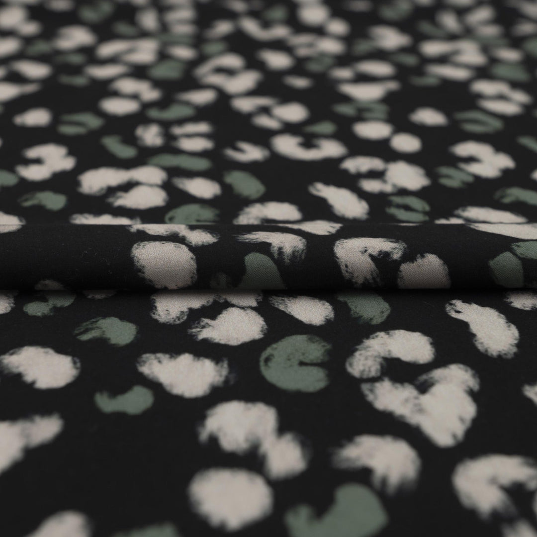Rayon Challis fabric in black with scattered olive dots, perfect for sewing blouses, dresses, and skirts.