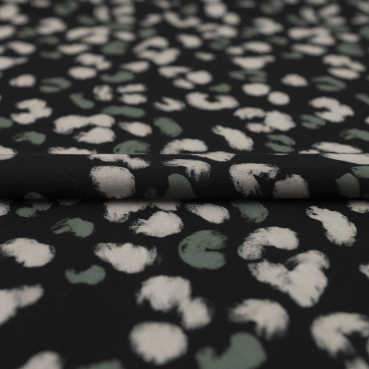 Rayon Challis fabric in black with scattered olive dots, perfect for sewing blouses, dresses, and skirts.