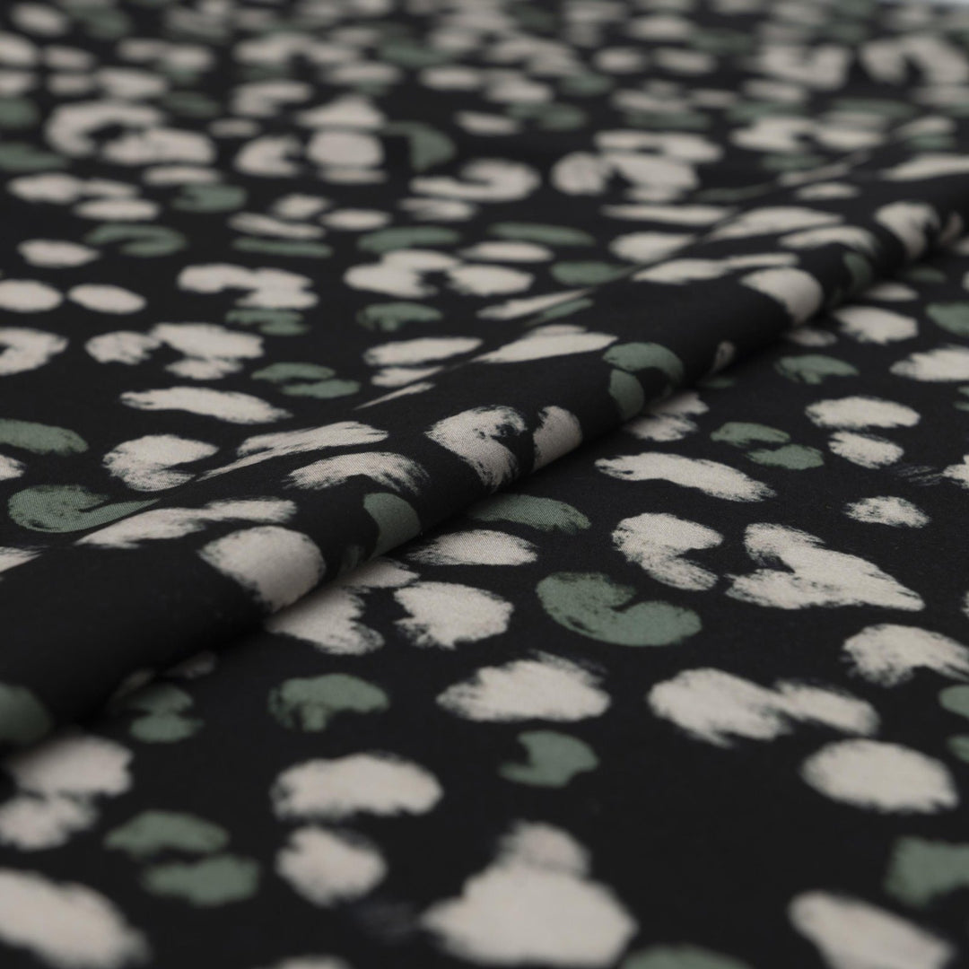 Rayon Challis fabric in black with scattered olive dots, perfect for sewing blouses, dresses, and skirts.