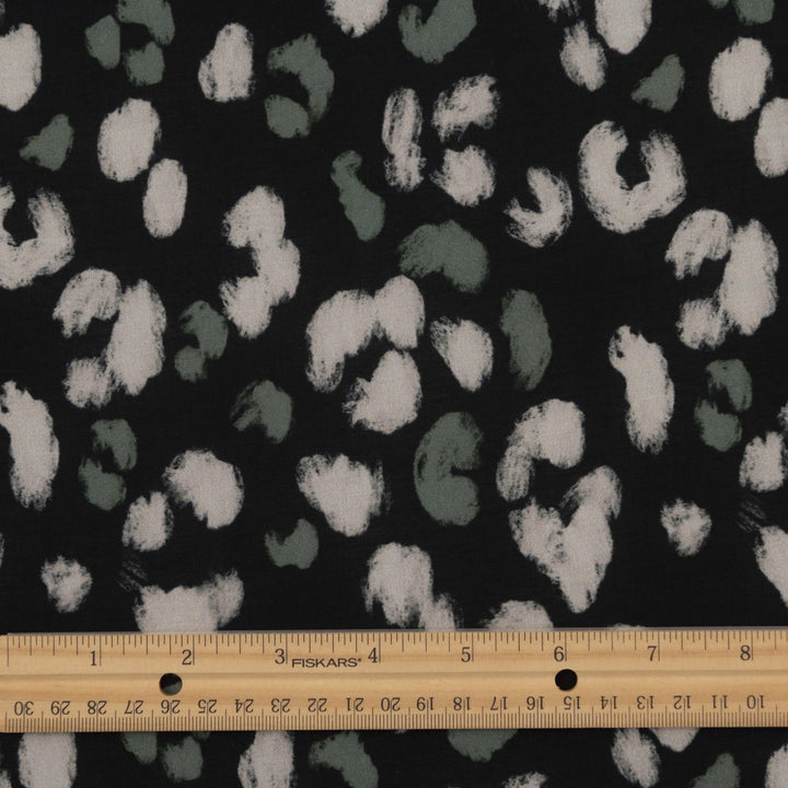 Rayon Challis fabric in black with scattered olive dots, perfect for sewing blouses, dresses, and skirts.