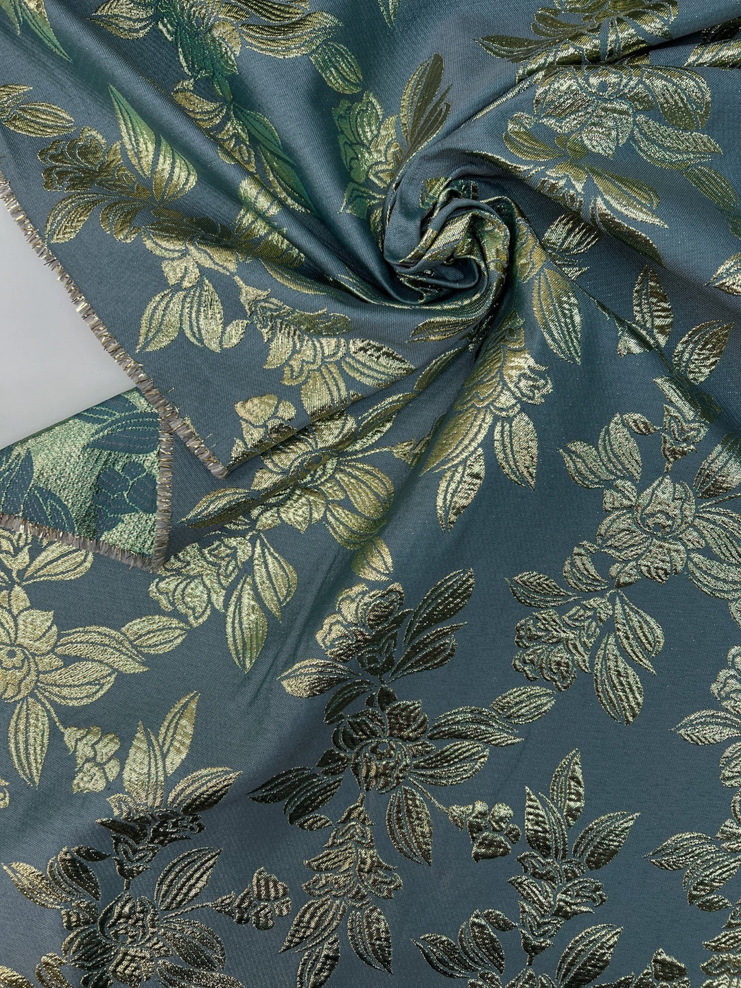 French jacquard fabric with metallic leaf pattern in teal and gold, polyester lurex acrylic blend, ideal for bridal gowns, evening dresses, and formalwear.