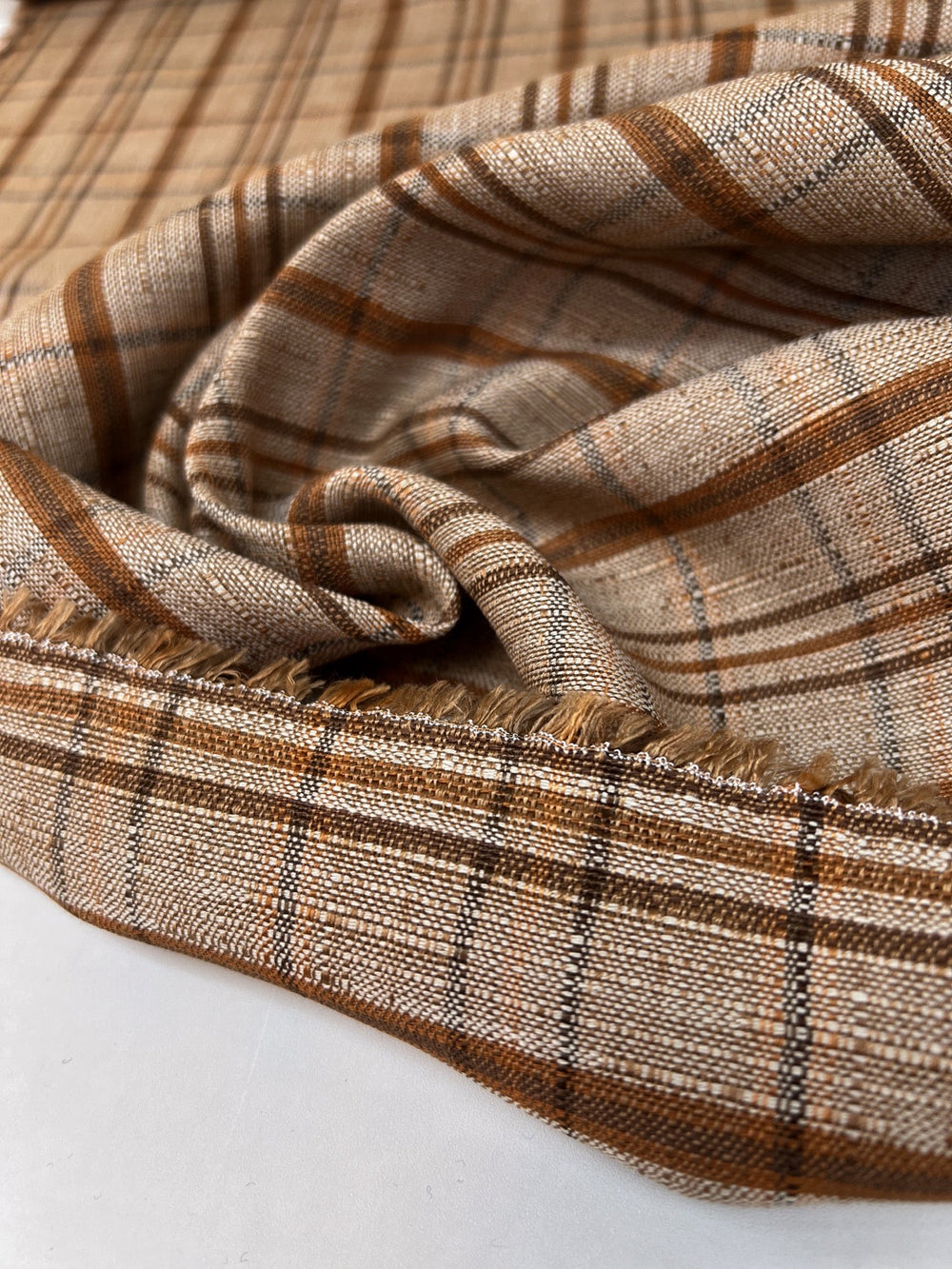 Italian plaid tweed fabric in browns and beige, viscose cotton blend, lightweight textile for structured coats, suiting, skirts, and dresses.