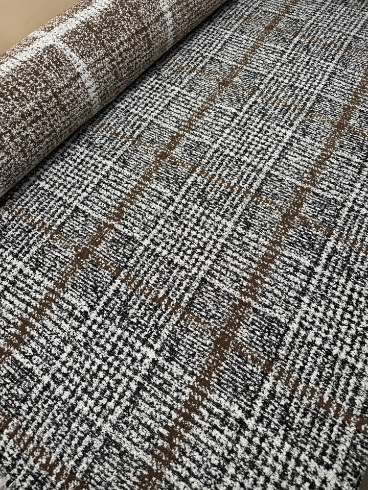 Close-up of Italian tweed fabric in wool and cotton blend, featuring white, black, and brown tones, ideal for coats, suits, and structured skirts.