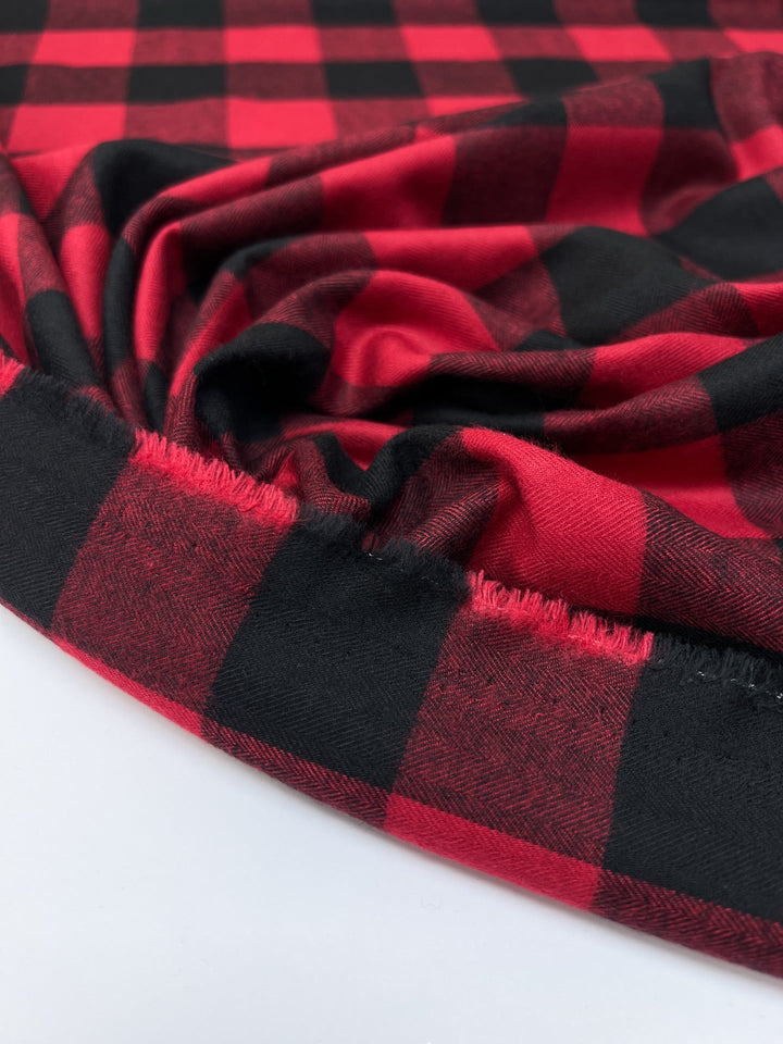 Italian cotton flannel fabric in red and black buffalo plaid, lightweight textile ideal for shirts, blouses, and casual wear.