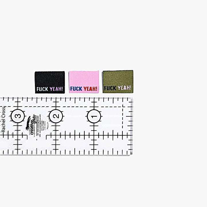 F*ck Yeah woven labels by Kylie and the Machine showing three color variations: black/blue/purple, khaki/black/pink, and pink/navy/rust side seam tags