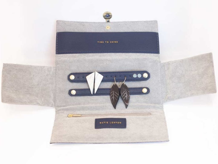 Travel Jewelry Organizer Roll in soft pink and navy faux-leather with compartments for rings, necklaces, and earrings.