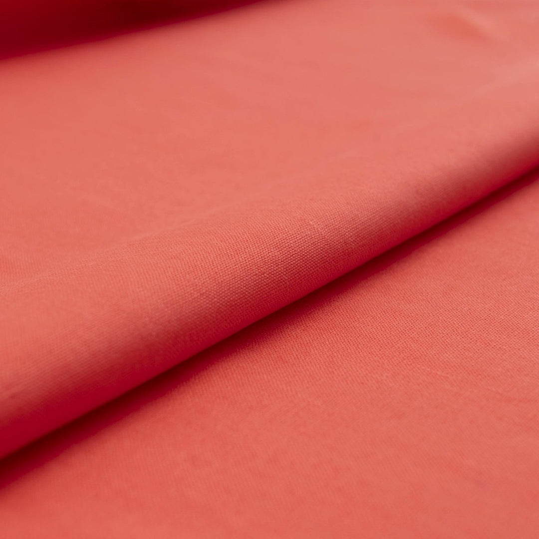 Bright living coral linen fabric with soft drape, breathable lightweight texture, ideal for sewing dresses, skirts, blouses, and summer clothing.


