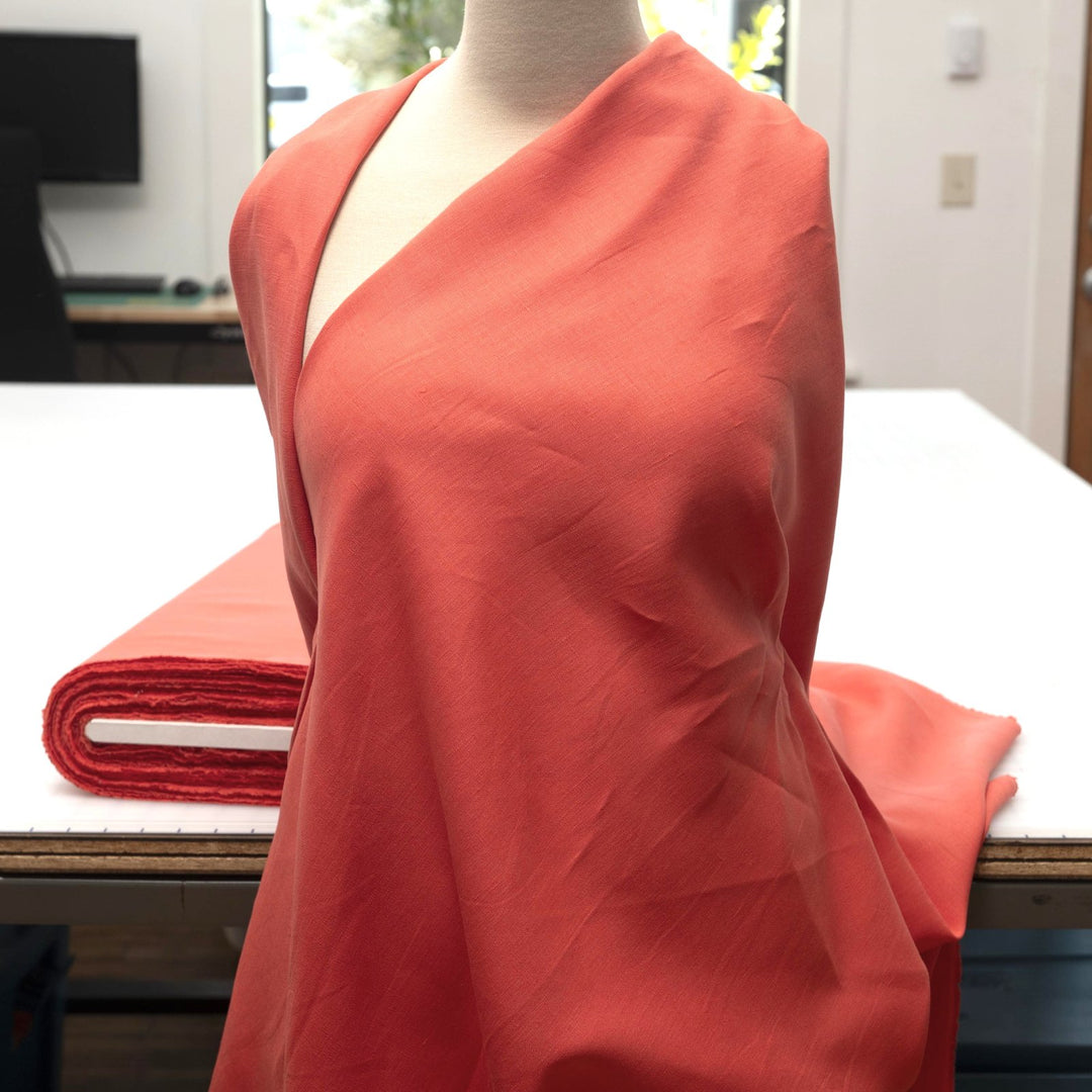 Bright living coral linen fabric with soft drape, breathable lightweight texture, ideal for sewing dresses, skirts, blouses, and summer clothing.

