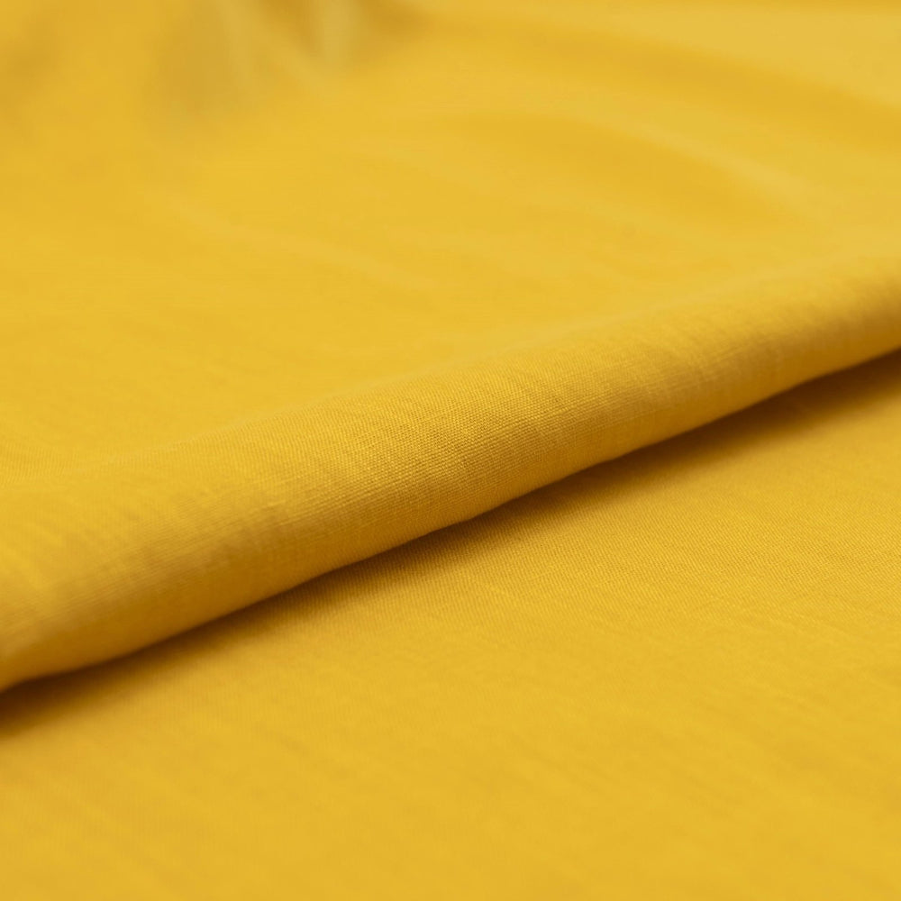 Bright summer marigold linen fabric with soft drape, breathable texture, and lightweight feel for sewing dresses, skirts, and summer apparel.