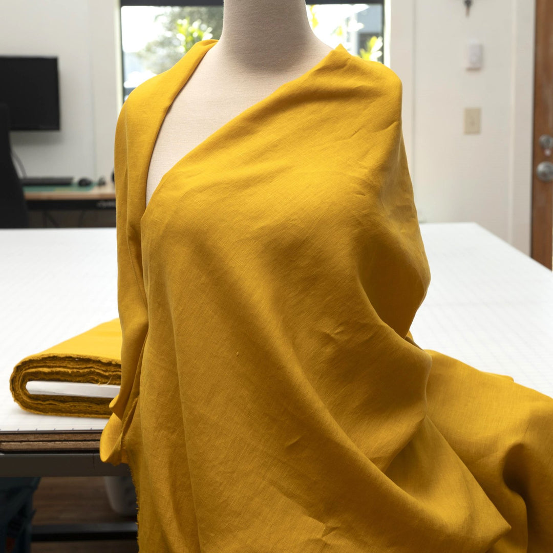 Bright summer marigold linen fabric with soft drape, breathable texture, and lightweight feel for sewing dresses, skirts, and summer apparel.