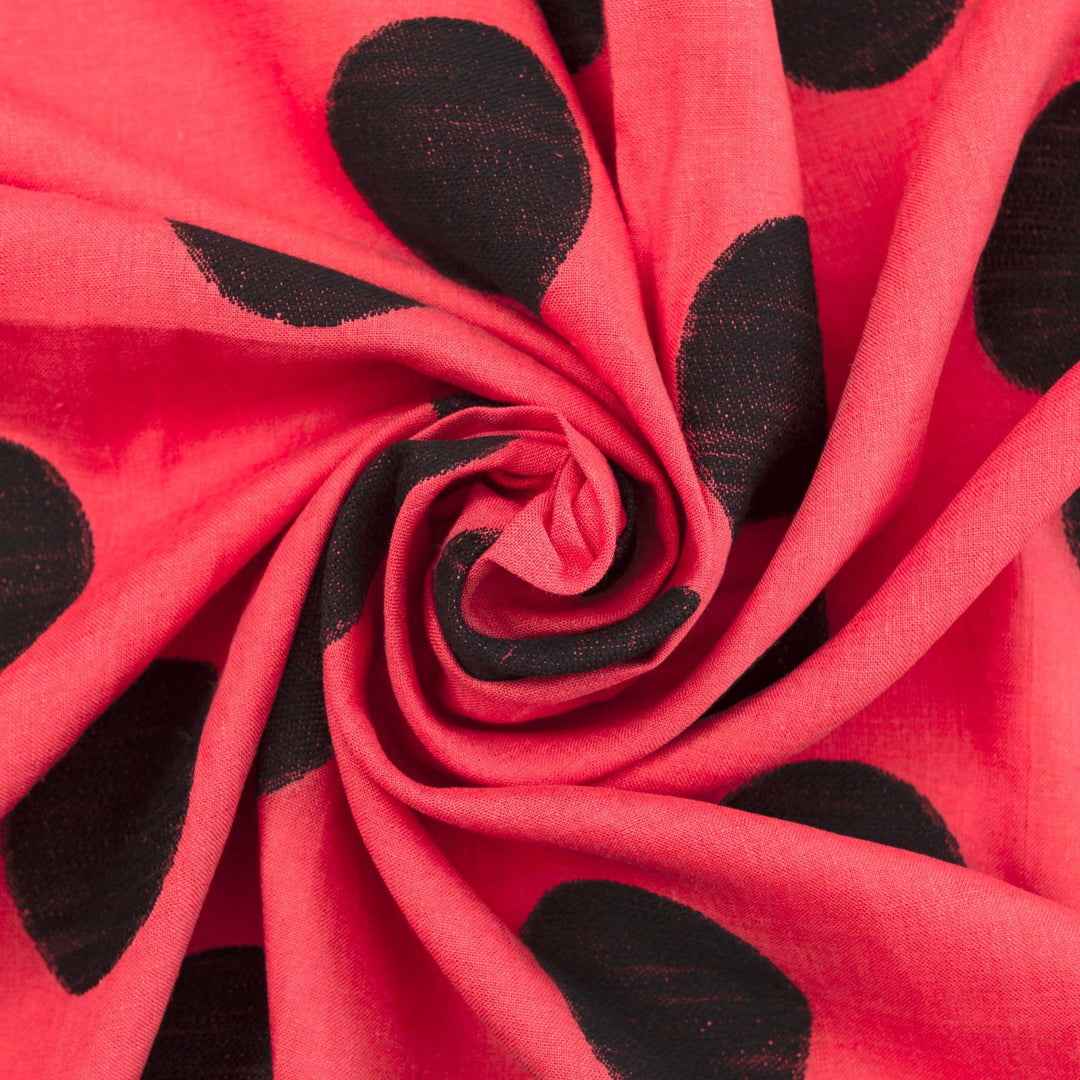 Sunset red-orange linen fabric with large 3-inch black embroidered polka dots, soft drape, and breathable medium-weight texture for stylish garments.

