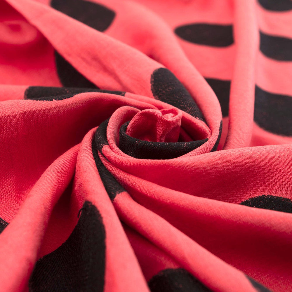 Sunset red-orange linen fabric with large 3-inch black embroidered polka dots, soft drape, and breathable medium-weight texture for stylish garments.

