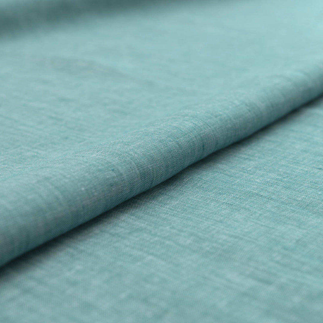Teal linen chambray fabric, lightweight and breathable, with a soft texture ideal for sewing dresses, tunics, blouses, and year-round apparel.


