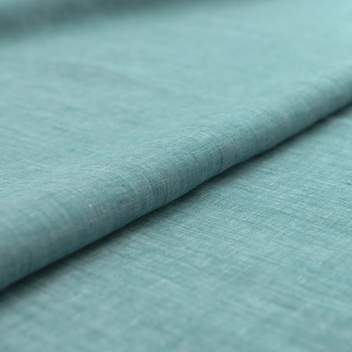 Teal linen chambray fabric, lightweight and breathable, with a soft texture ideal for sewing dresses, tunics, blouses, and year-round apparel.

