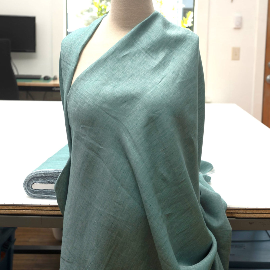 Teal linen chambray fabric, lightweight and breathable, with a soft texture ideal for sewing dresses, tunics, blouses, and year-round apparel.

