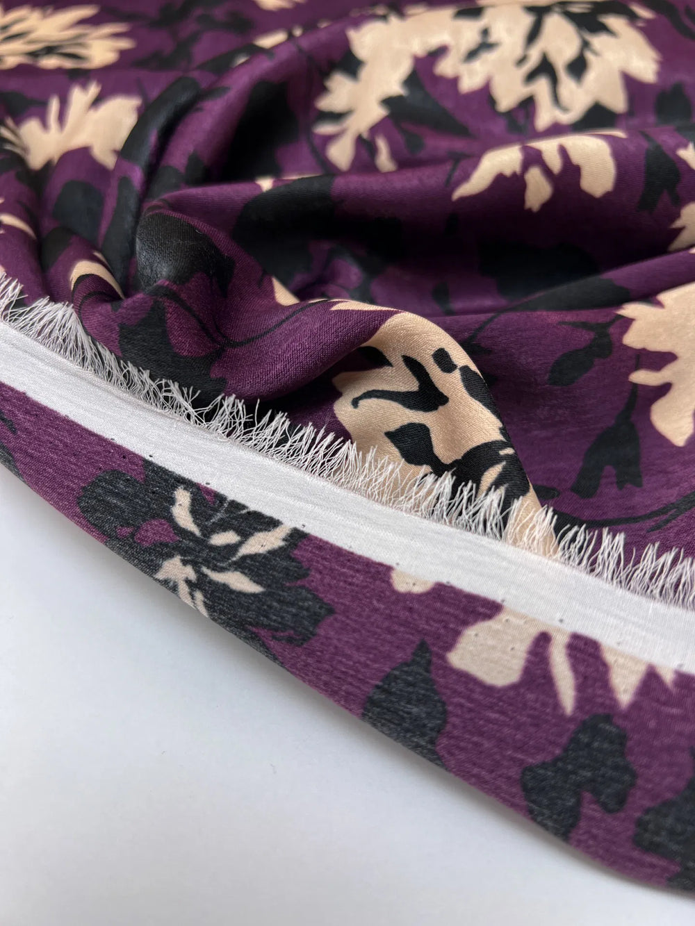 Italian dressweight sateen fabric with purple, black, and beige leaf pattern, lightweight polyester textile ideal for structured dresses, skirts, and suiting.