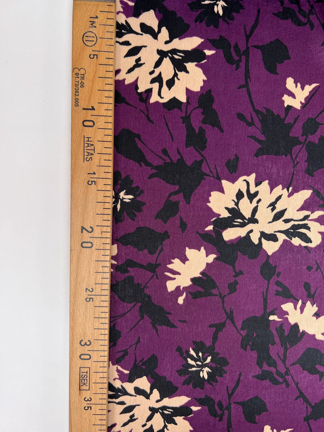 Italian dressweight sateen fabric with purple, black, and beige leaf pattern, lightweight polyester textile ideal for structured dresses, skirts, and suiting.