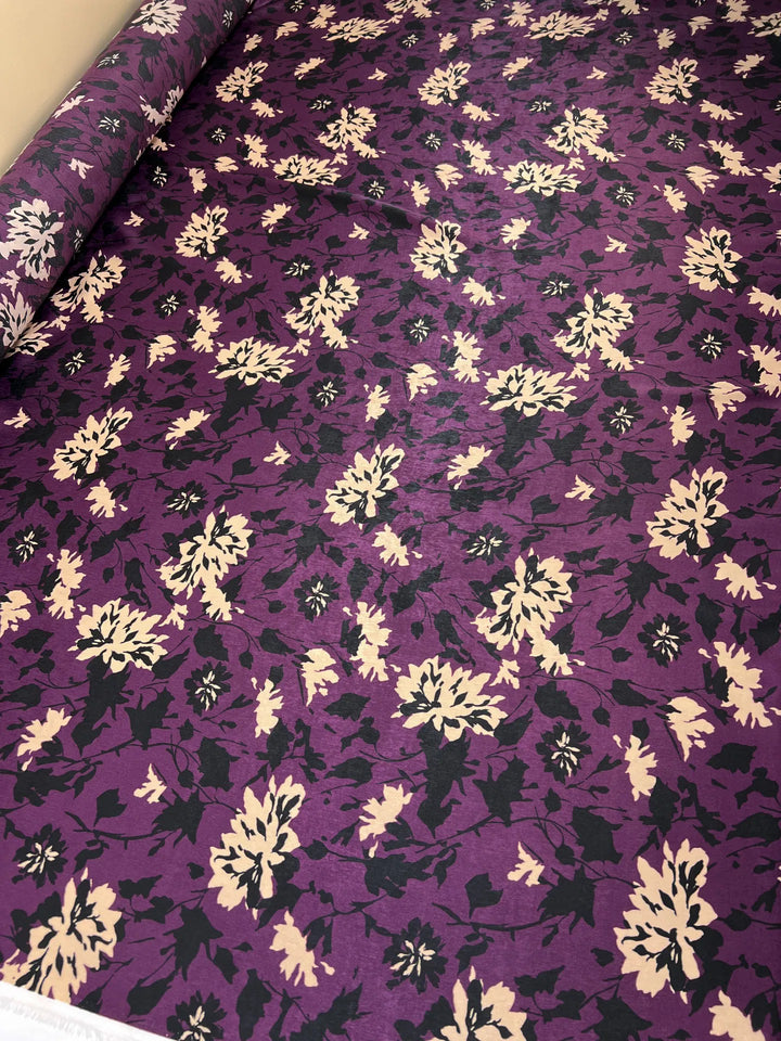 Italian dressweight sateen fabric with purple, black, and beige leaf pattern, lightweight polyester textile ideal for structured dresses, skirts, and suiting.