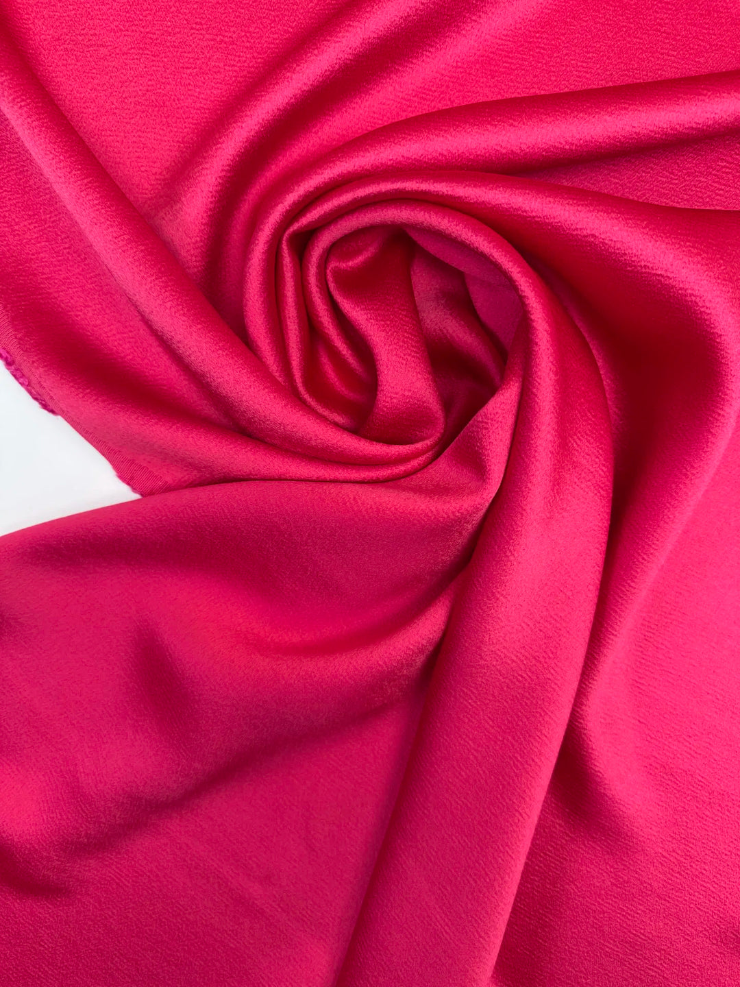Luxurious Rayon Satin fabric in bright pink with a textured finish. Made from 65% Acetate and 35% Rayon/Viscose. Ideal for dresses, skirts, and blouses.