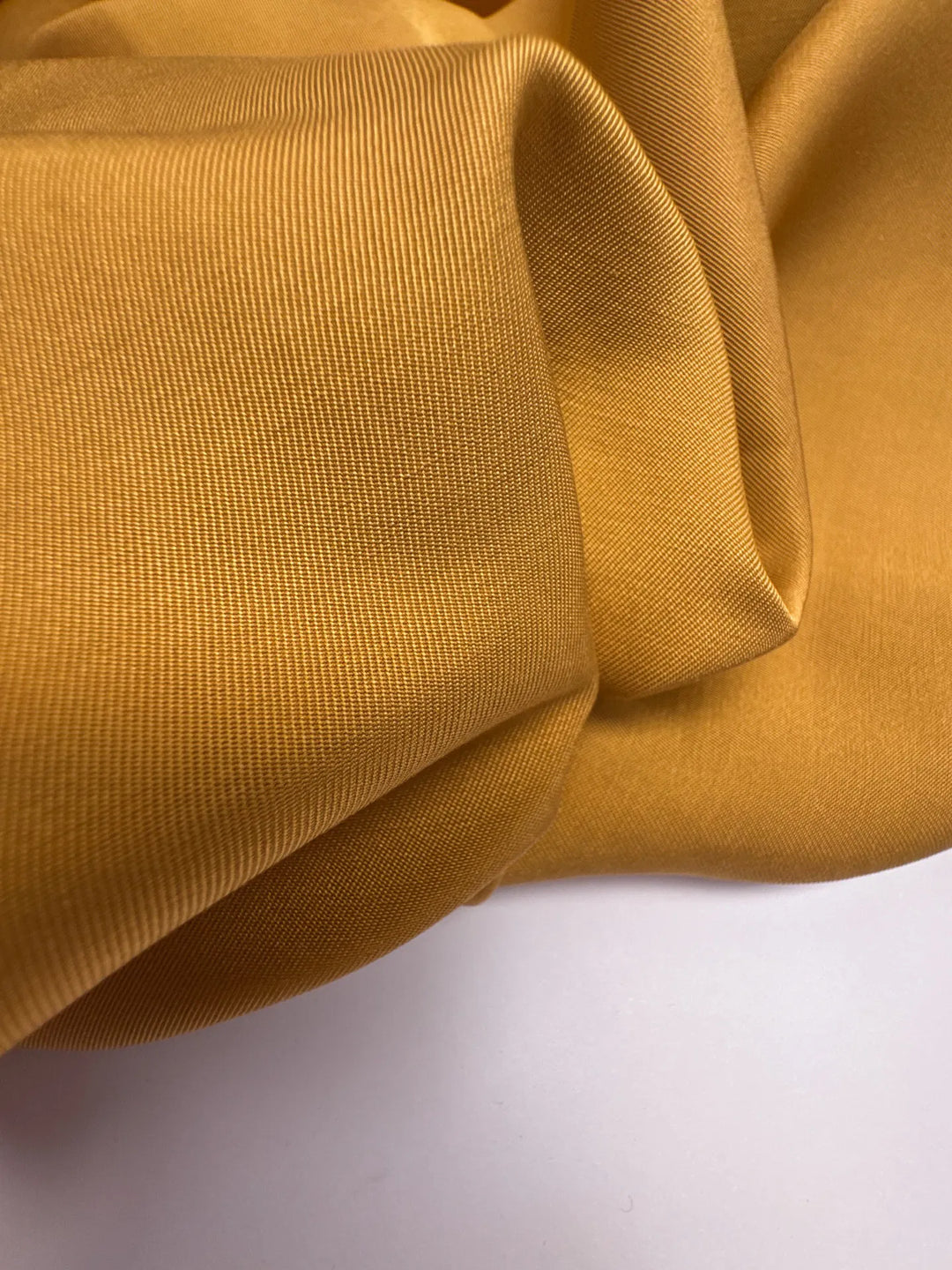 Premium Silk Twill fabric in mustard yellow color. Made from 100% pure silk. Ideal for unstructured dresses, skirts, and blouses.