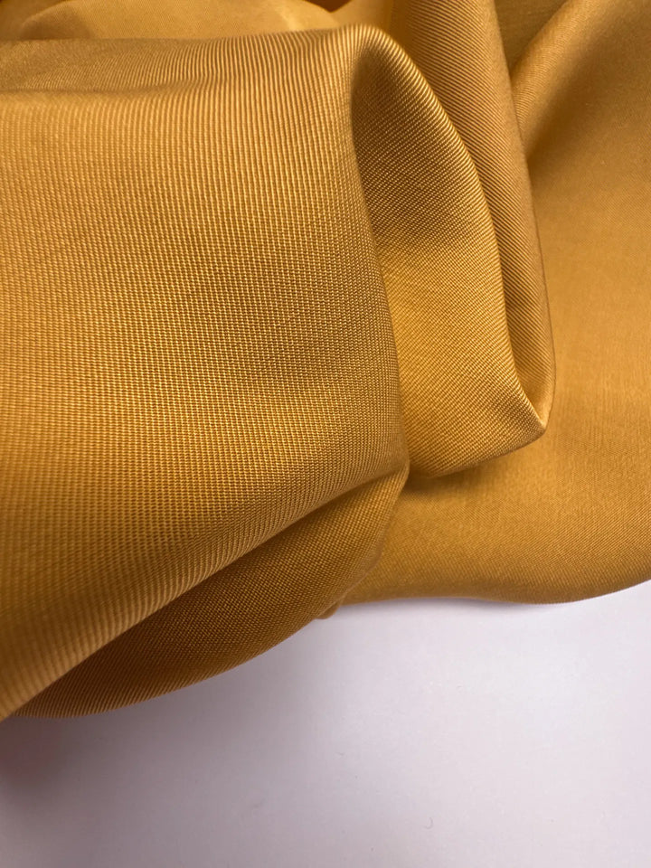 Premium Silk Twill fabric in mustard yellow color. Made from 100% pure silk. Ideal for unstructured dresses, skirts, and blouses.
