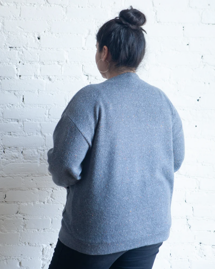 True Bias Marlo Sweater in cozy medium-weight knit with deep V-neck and large buttons, shown in mid-thigh length with patch pockets.