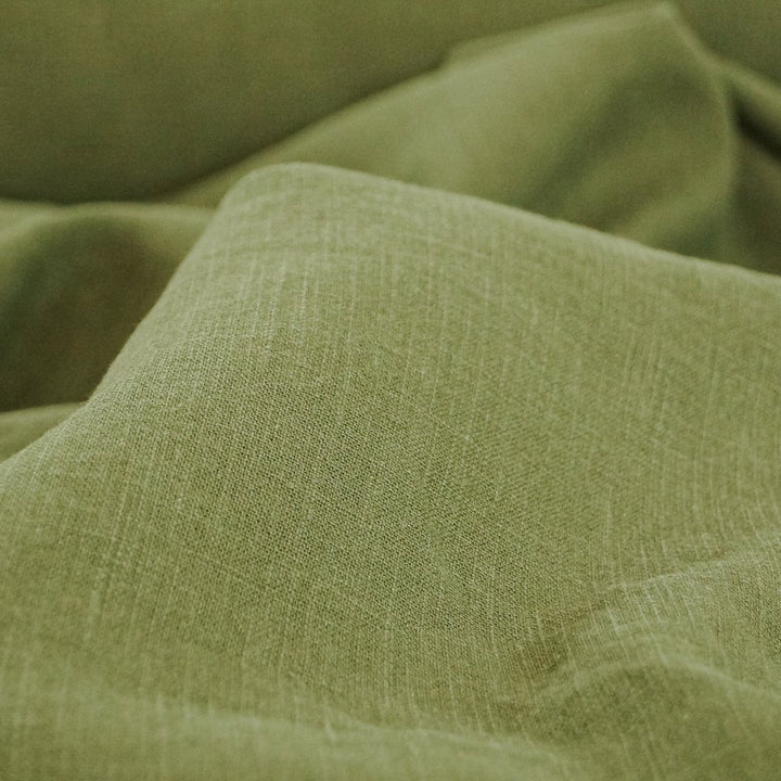 Soft Wash Linen fabric in rich olive green color, 100% pre-washed linen ideal for sewing dresses, jackets, pants, and more.

