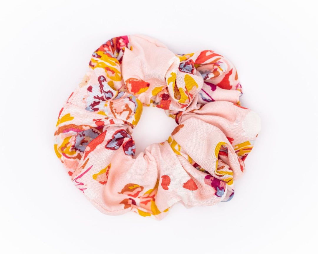 A collection of colorful, soft fabric scrunchies in various patterns and designs, perfect for matching with accessories like robes and makeup bags.