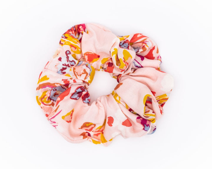 A collection of colorful, soft fabric scrunchies in various patterns and designs, perfect for matching with accessories like robes and makeup bags.