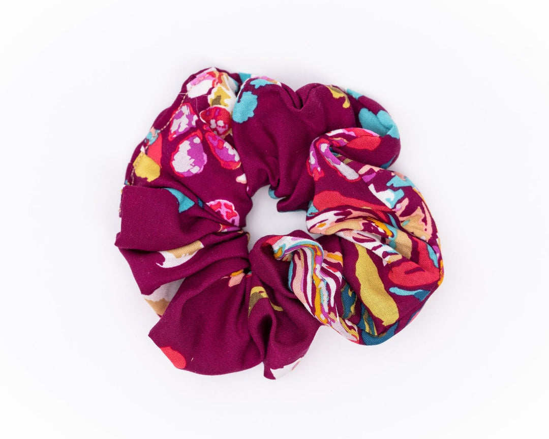 A collection of colorful, soft fabric scrunchies in various patterns and designs, perfect for matching with accessories like robes and makeup bags.