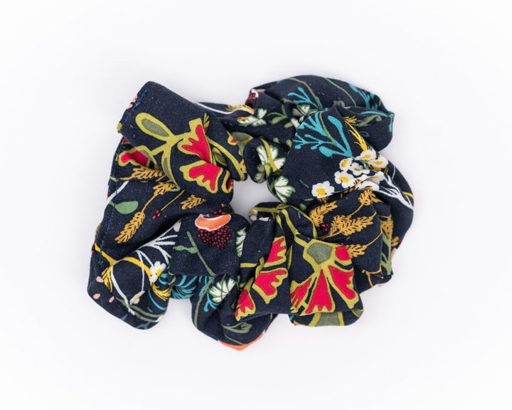 A collection of colorful, soft fabric scrunchies in various patterns and designs, perfect for matching with accessories like robes and makeup bags.