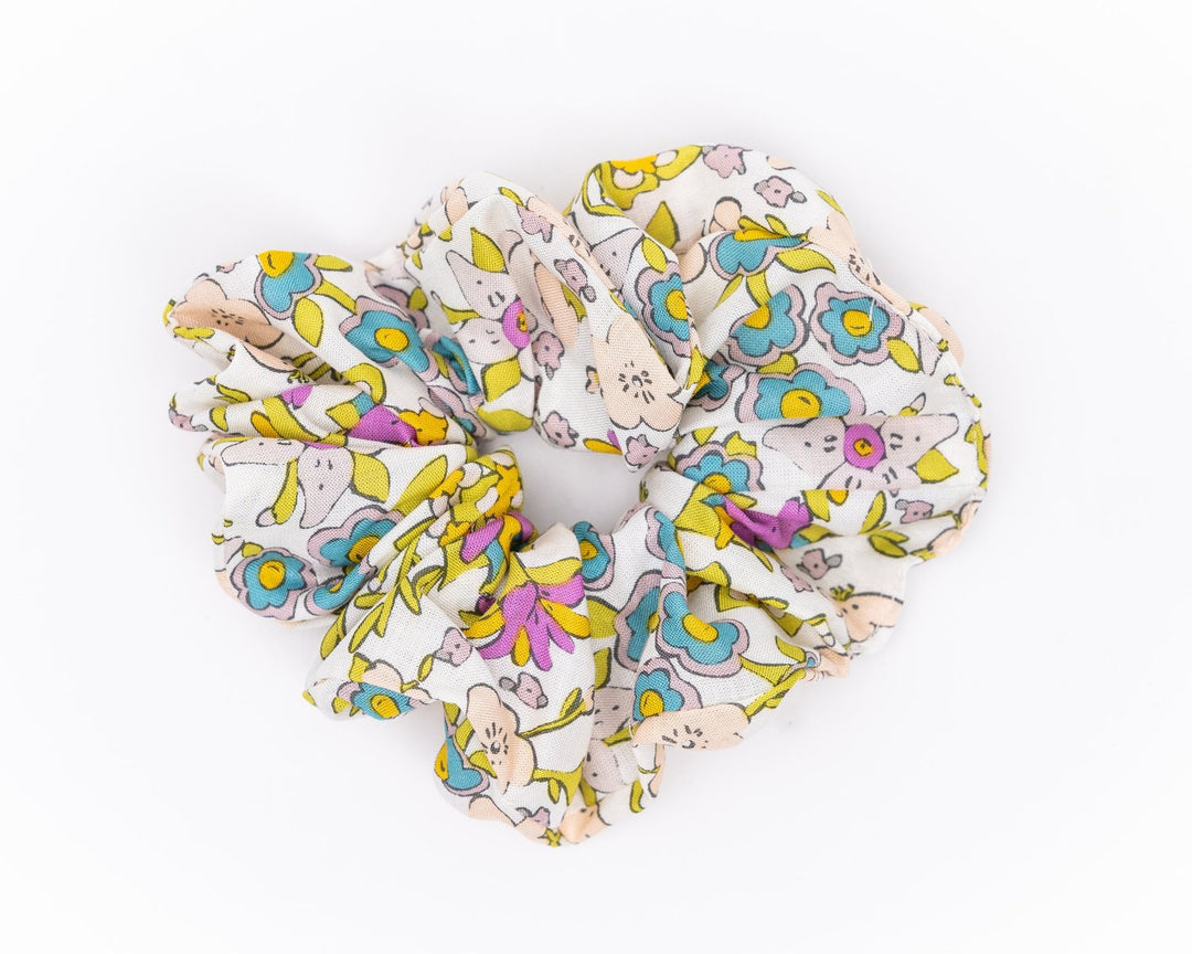 A collection of colorful, soft fabric scrunchies in various patterns and designs, perfect for matching with accessories like robes and makeup bags.
