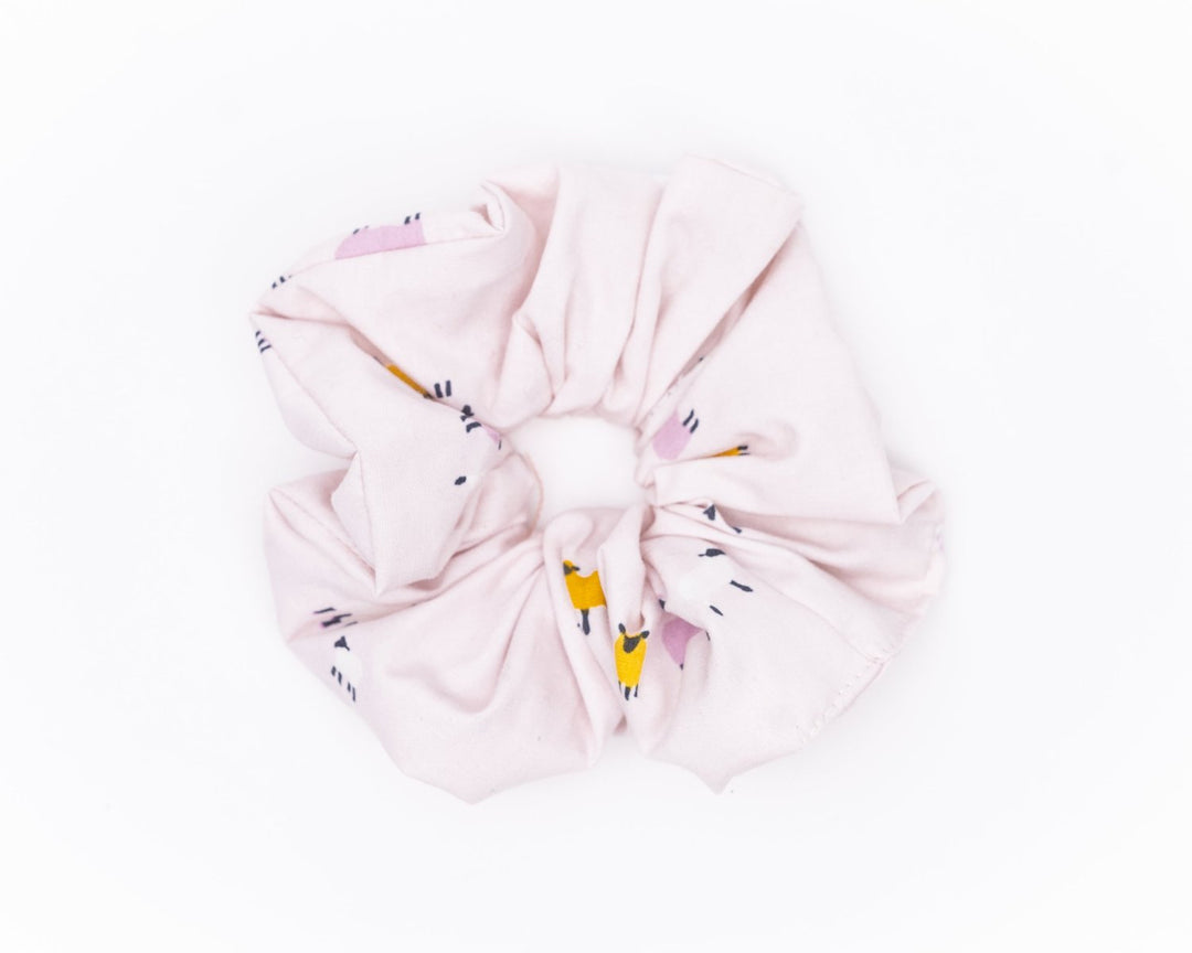 A collection of colorful, soft fabric scrunchies in various patterns and designs, perfect for matching with accessories like robes and makeup bags.